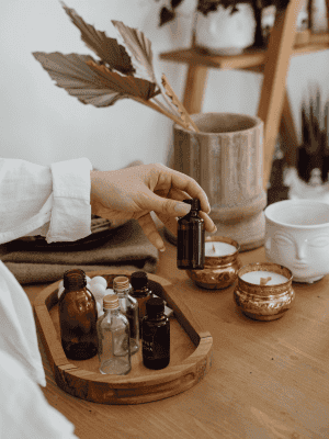 A person preparing essential oils for Thai massage therapy in a cozy, well-lit treatment room in Gla.