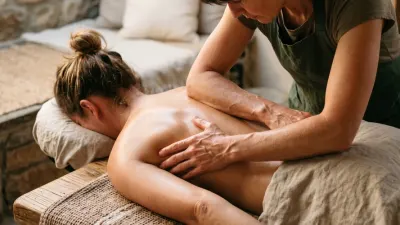 Massage therapist applying deep forearm pressure to a client's upper back
